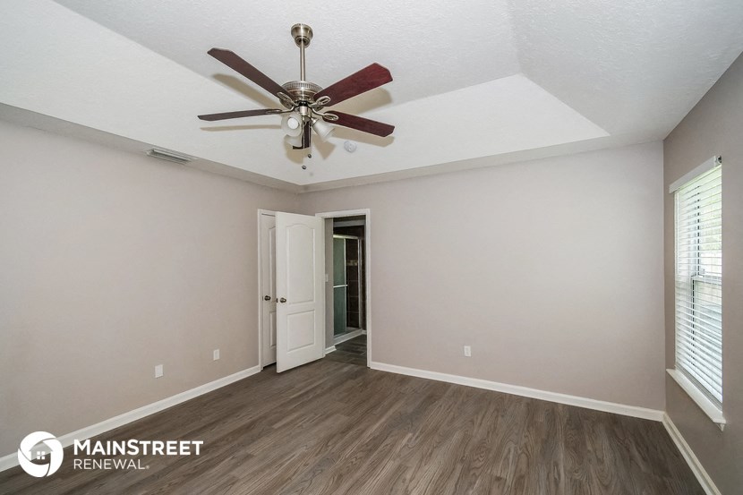 the spacious living room with ceiling fan and wood flooring