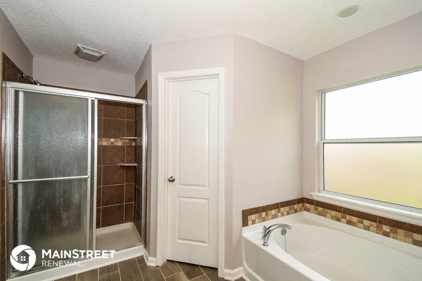 the master bathroom has a large tub and a walk in shower
