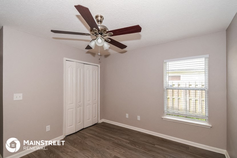 the interior of a bedroom with a ceiling fan and a window