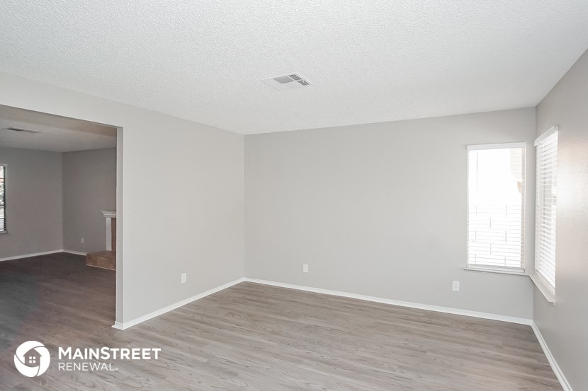 the spacious living room with wood flooring and white walls