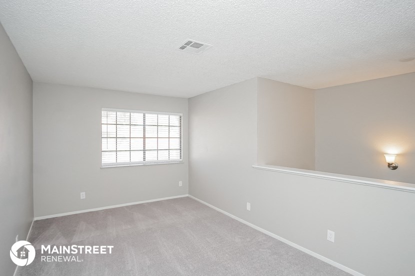 the spacious living room with white carpet and a window