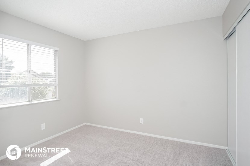 a bedroom with a large window and a carpeted floor