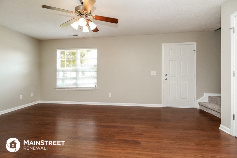 a living room with wood floors and a ceiling fan