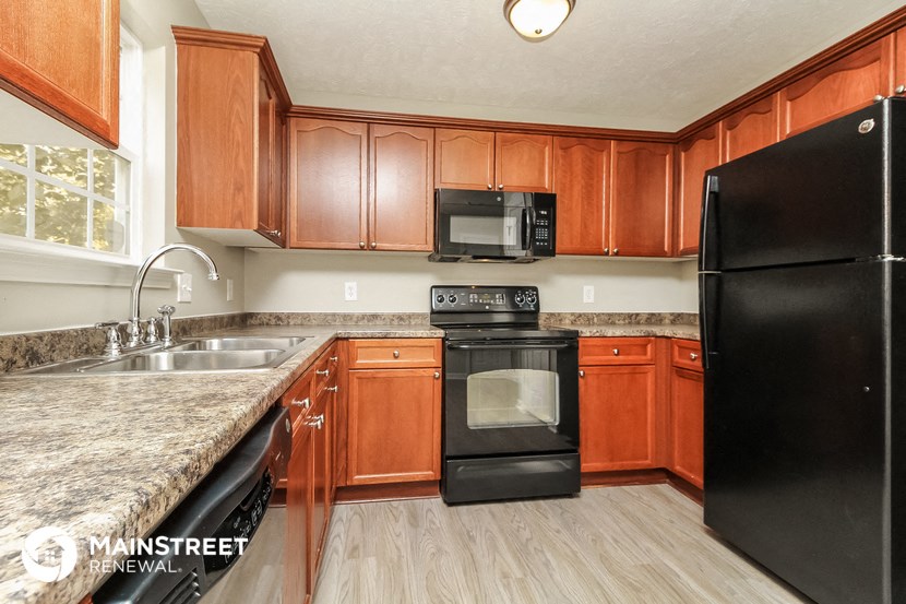 a kitchen with black appliances and wooden cabinets and granite counter tops