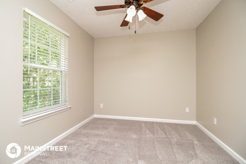 the spacious living room has a ceiling fan and a large window