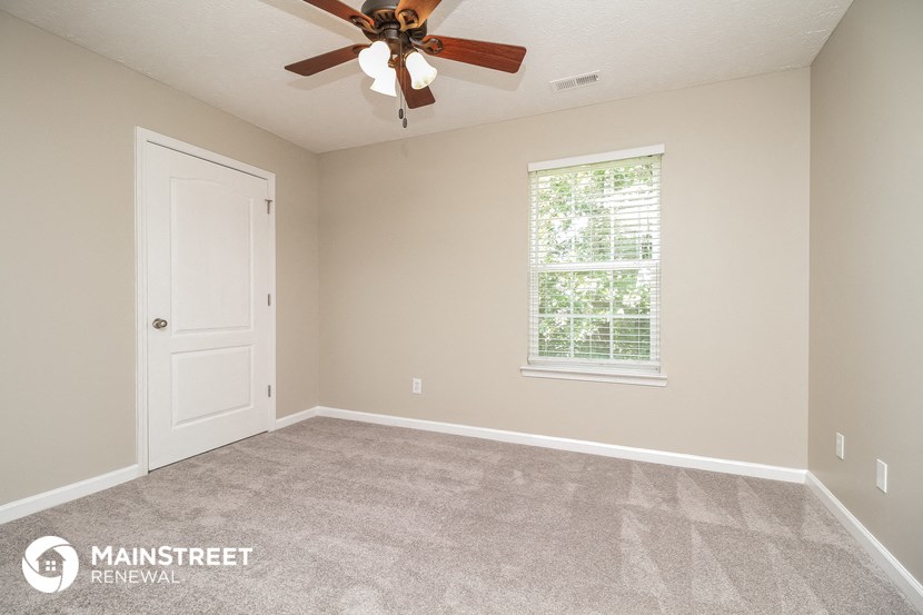 the master bedroom has a carpeted floor and a ceiling fan