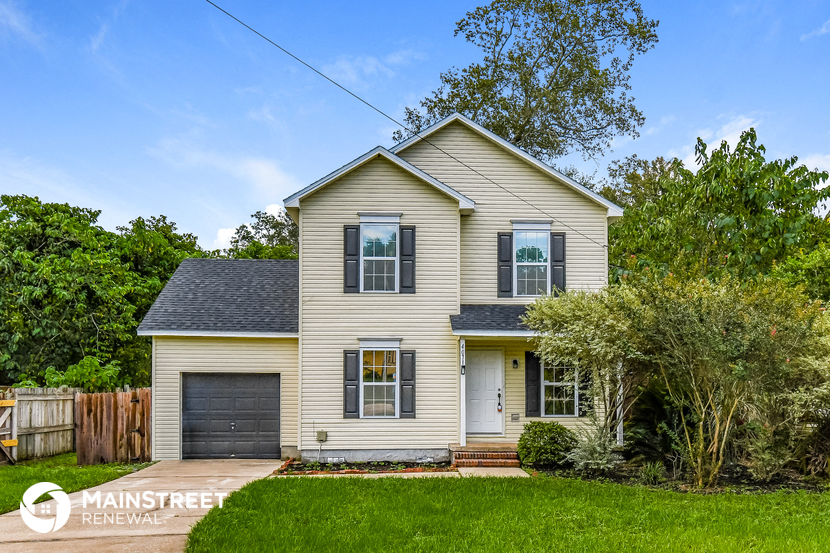 a yellow house with a black garage door and a green lawn