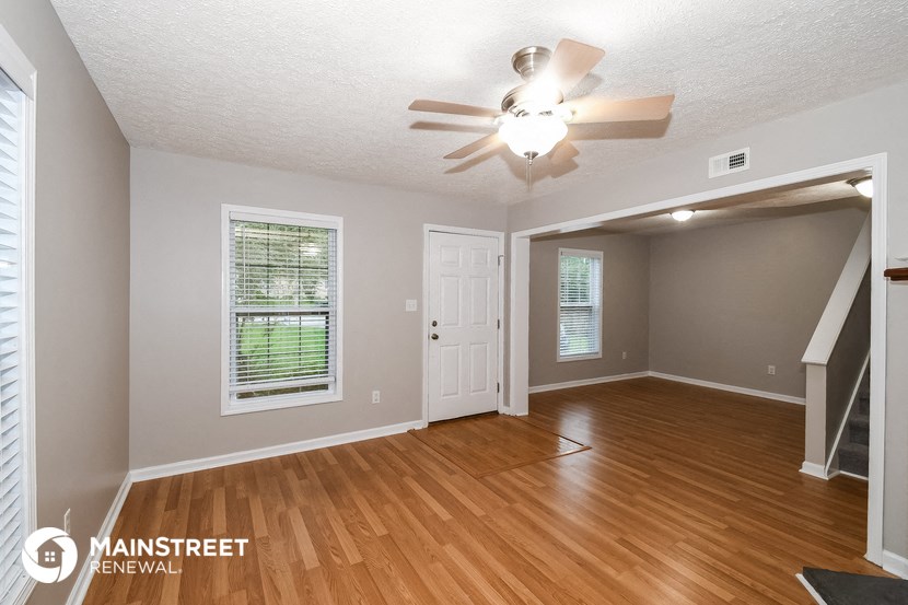 the living room of an empty house with a ceiling fan