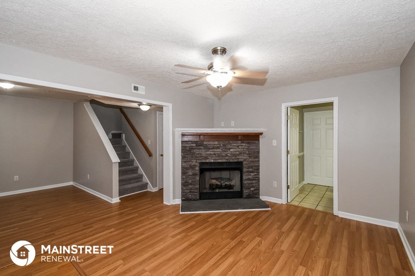 the living room of a house with a fireplace and a ceiling fan