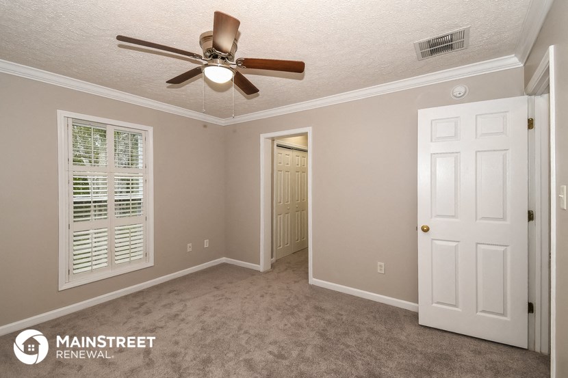 a bedroom with a ceiling fan and a door to a closet