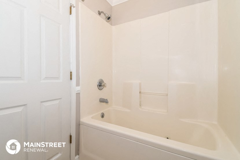 a white bathroom with a tub and a white door