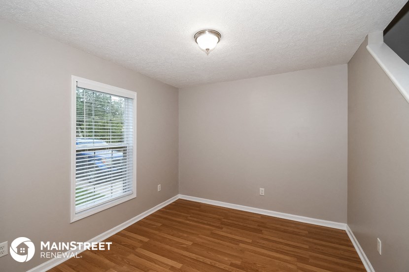 the interior of an empty room with wood flooring and a large window
