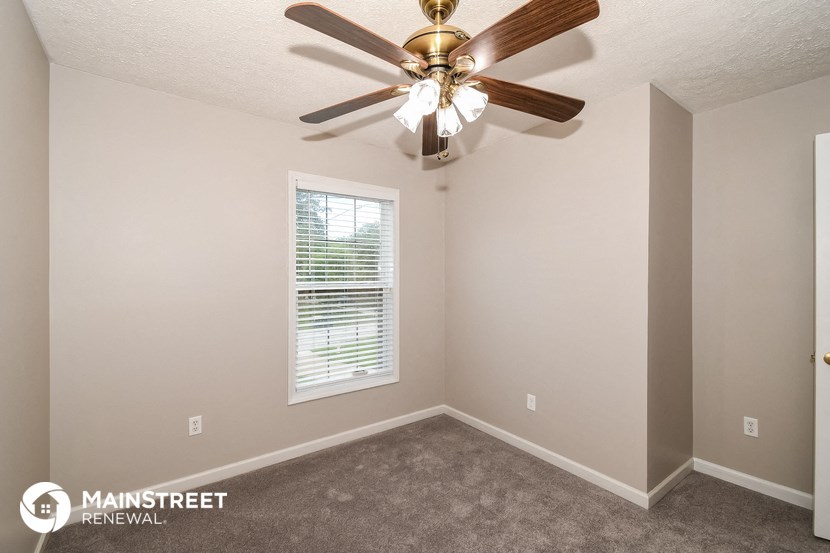 the interior of a bedroom with a ceiling fan and a window