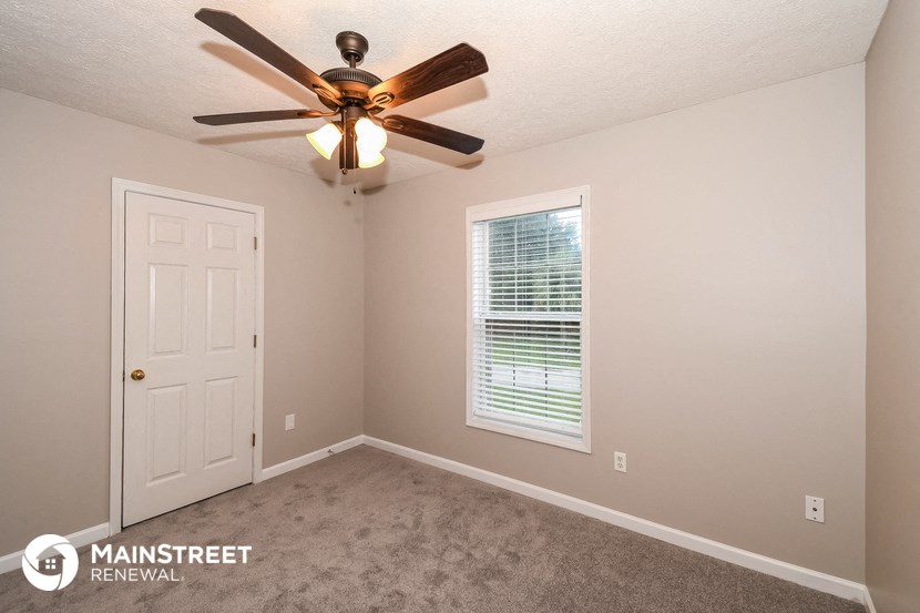 the upstairs bedroom has a ceiling fan and a white door