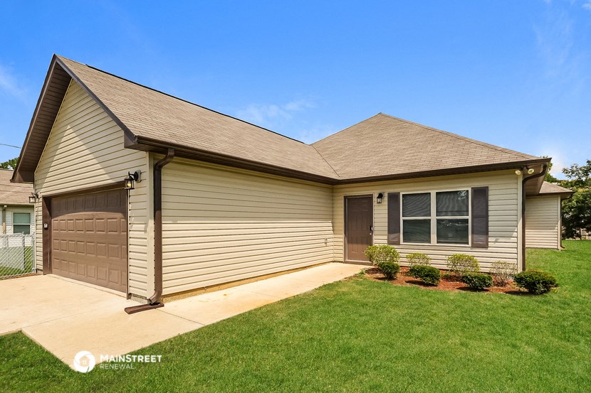 a tan house with a driveway and a garage door