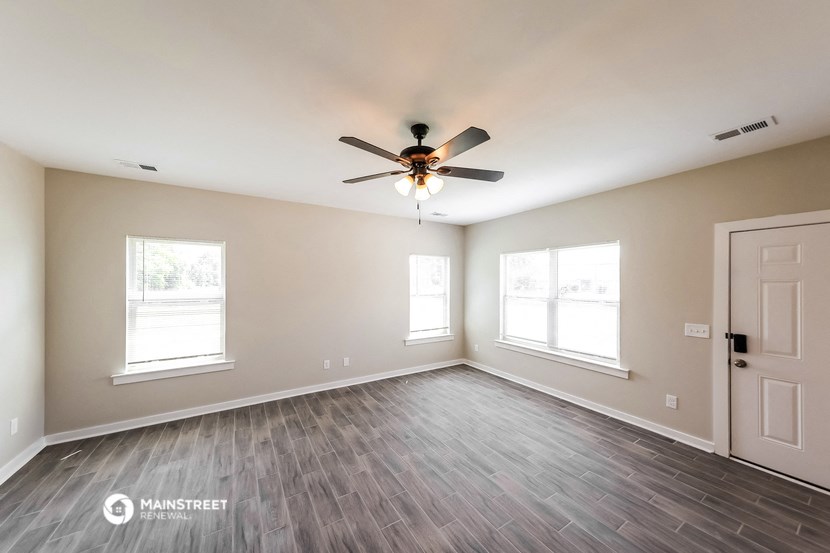 the living room with wood flooring and a ceiling fan