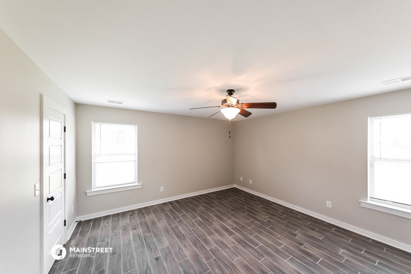 the spacious living room with wood flooring and a ceiling fan