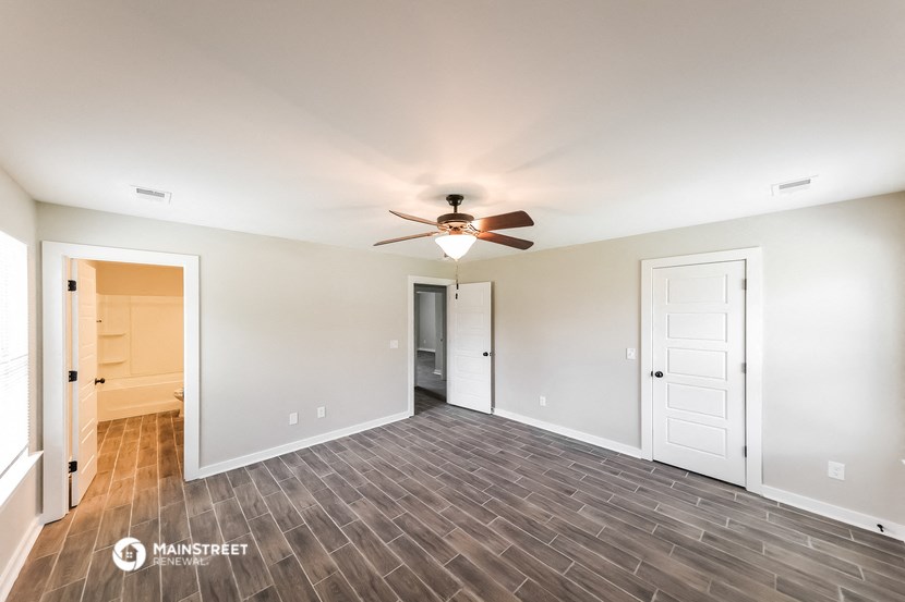 the spacious living room with wood flooring and a ceiling fan