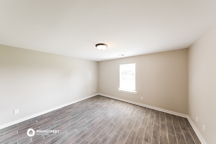 the spacious living room with wood flooring and a window