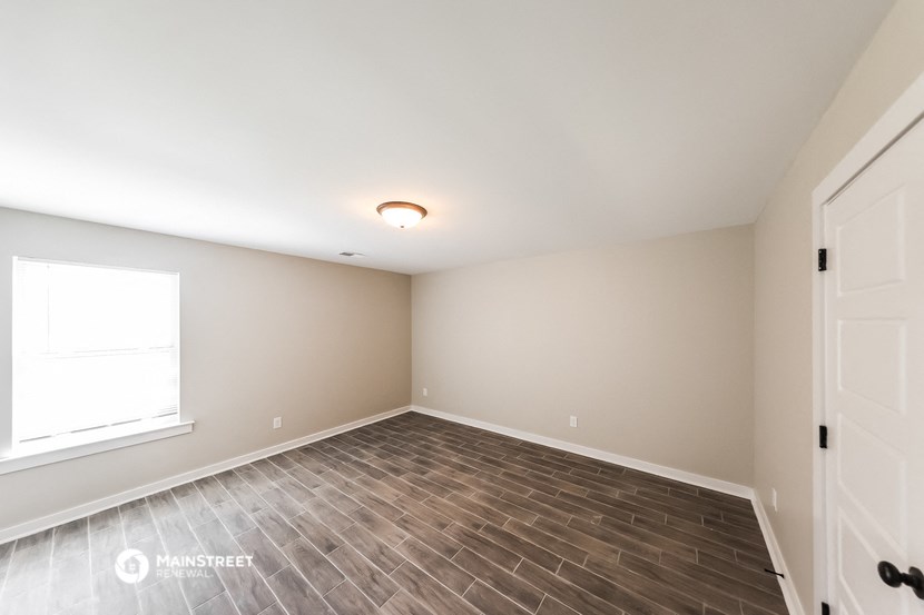 the spacious living room with wood flooring and a window