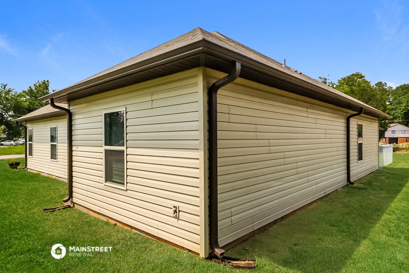 a detached garage with white siding on the side of a house
