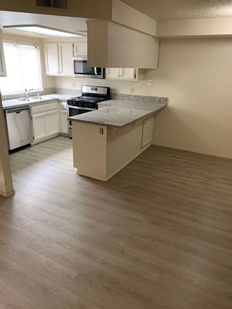 an empty kitchen with white cabinets and a counter top