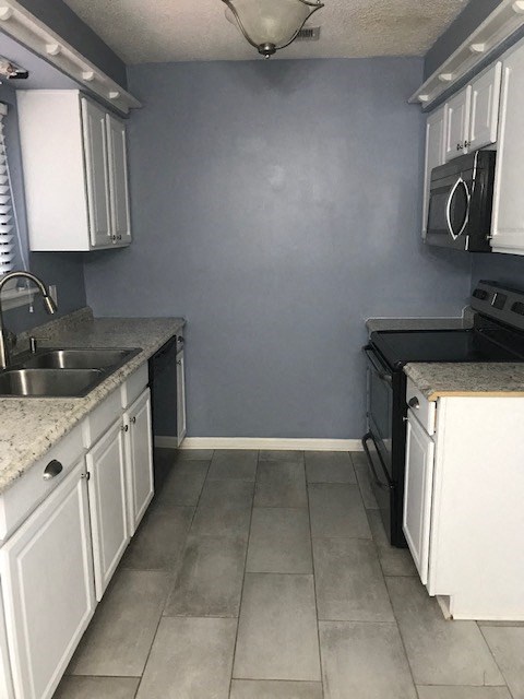 an empty kitchen with white cabinets and a sink