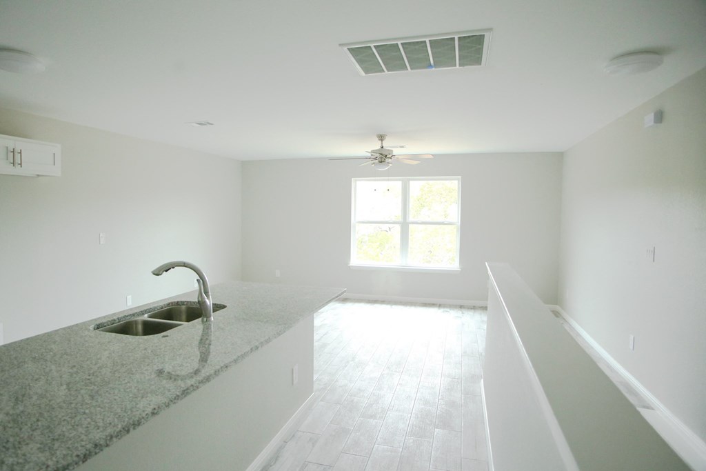 an empty kitchen with a sink and a ceiling fan