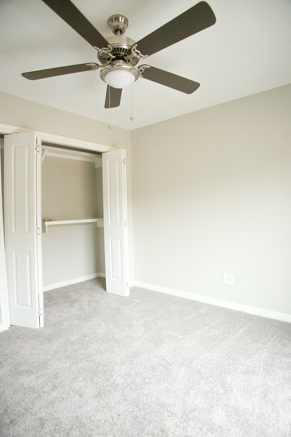 an empty bedroom with a ceiling fan and a closet