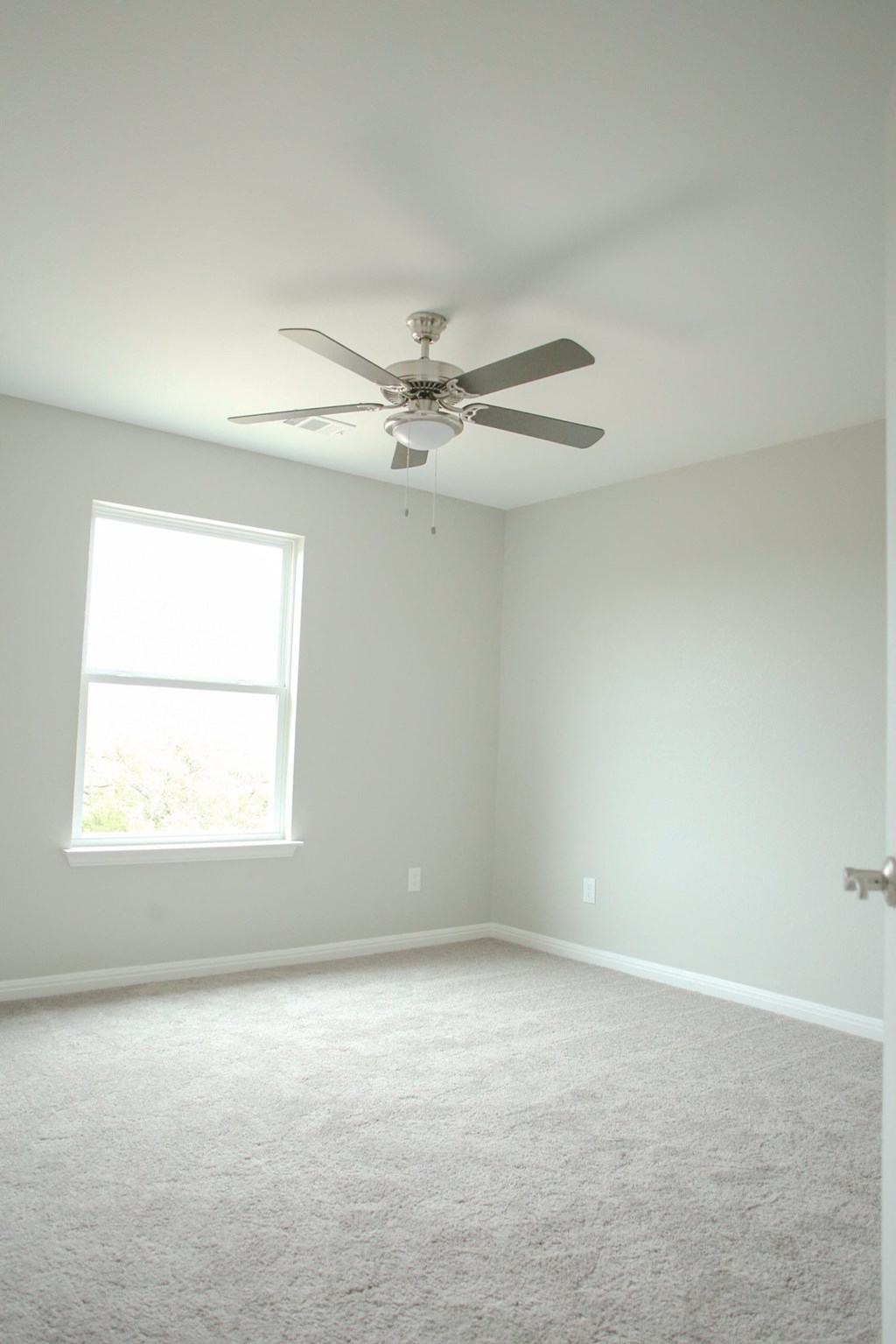 an empty room with a ceiling fan and a window
