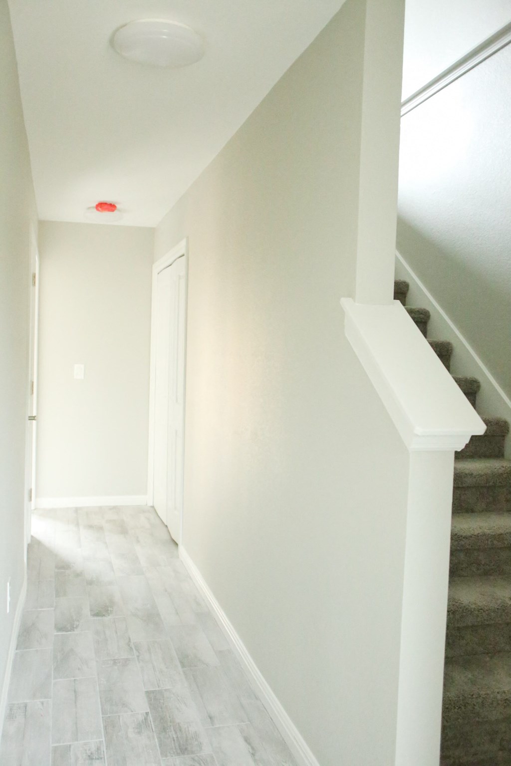 an empty hallway with a staircase and white walls and a white door