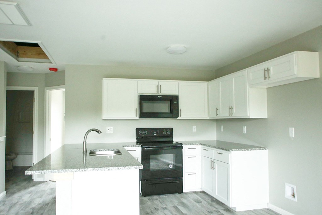 an empty kitchen with white cabinets and black appliances