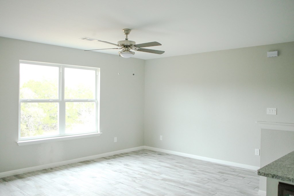 an empty room with a ceiling fan and a window