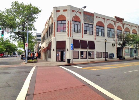A street view of a building with a red brick sidewalk.