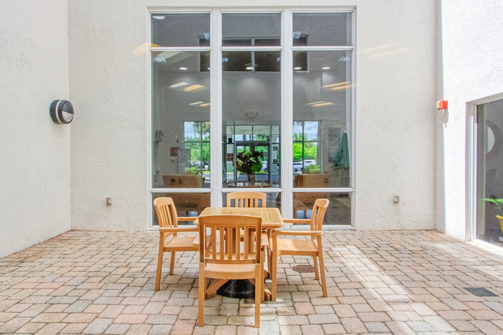 table and chairs on outside patio beside large window