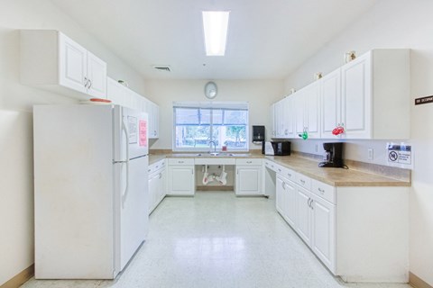 a kitchen with white cabinets and white appliances and a window