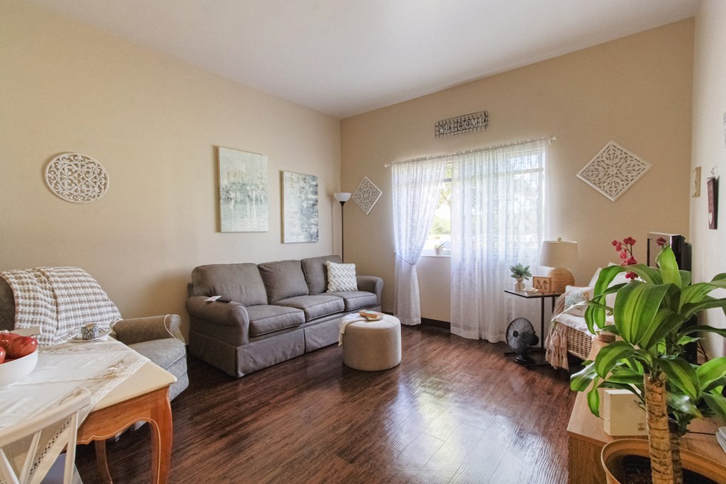living room with hardwood-style flooring, large window, and model furnishings