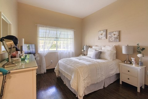 bedroom with hardwood-style floors, large windows, and model furniture