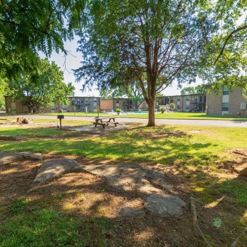 Apartments for Rent in Murfreesboro, TN - Condos at the Villager - Community Grounds With Picnic Table, Ample Grassy Areas, and Trees Providing Shade