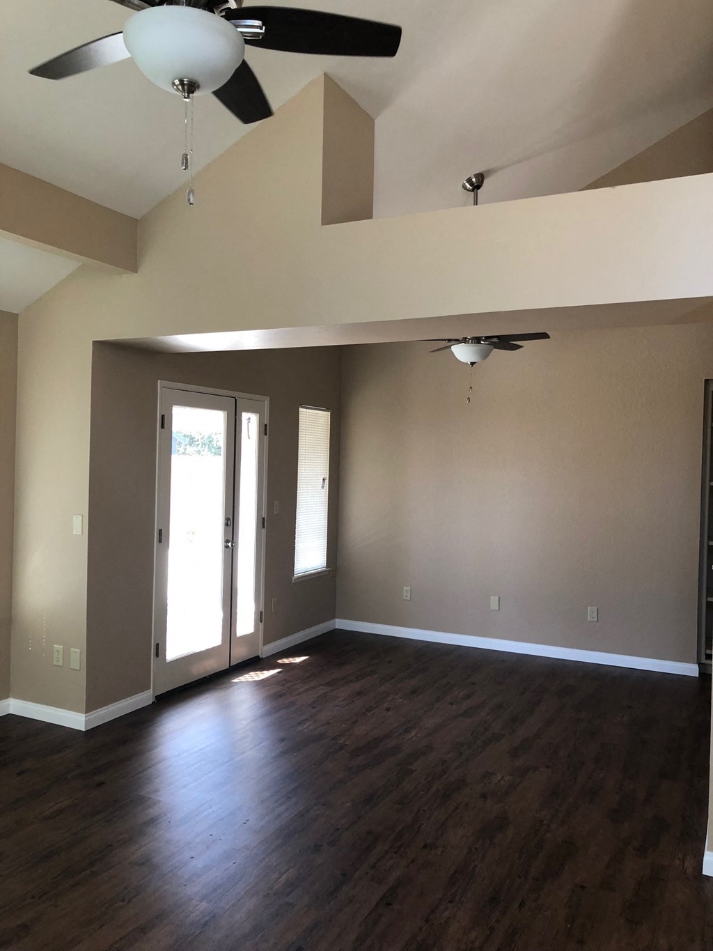an empty living room with wooden floors and a ceiling fan
