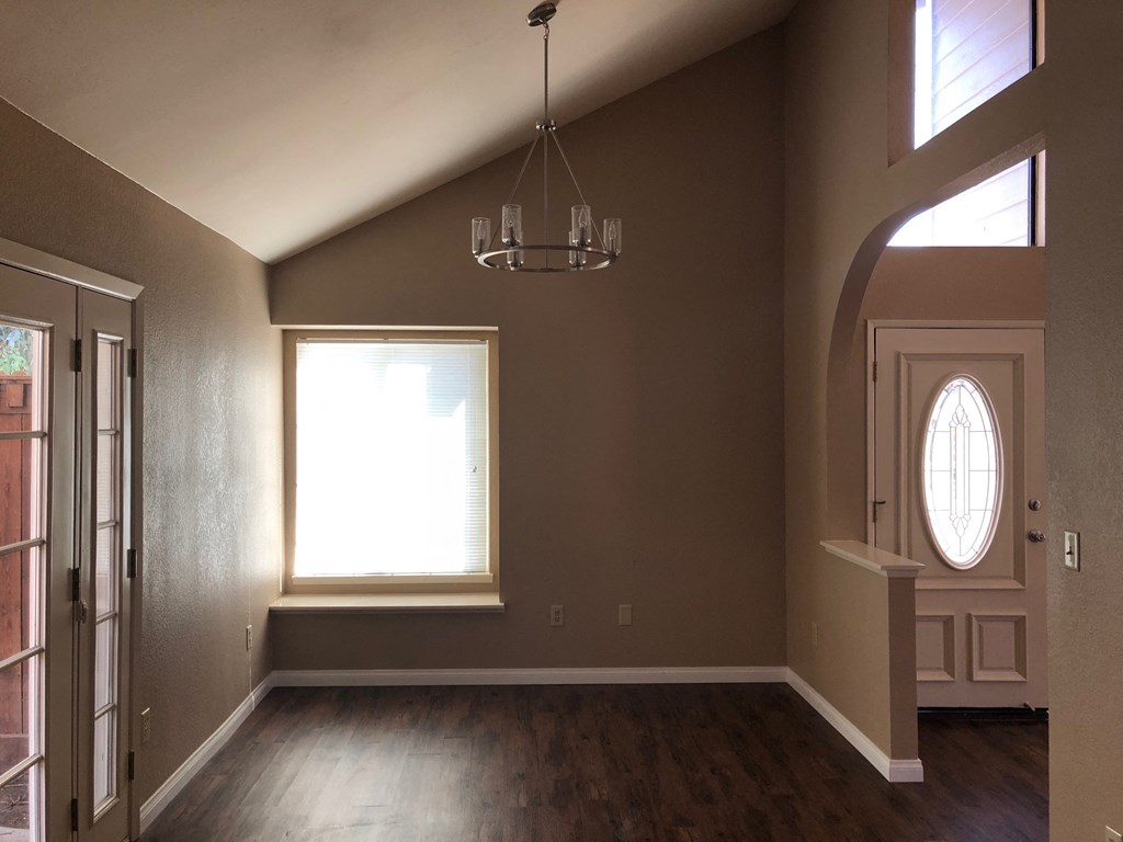 an empty living room with a window and a chandelier