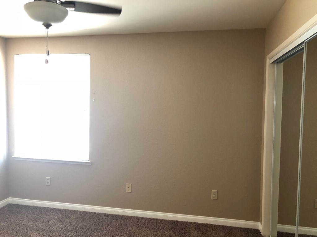 a empty room with a window and a ceiling fan