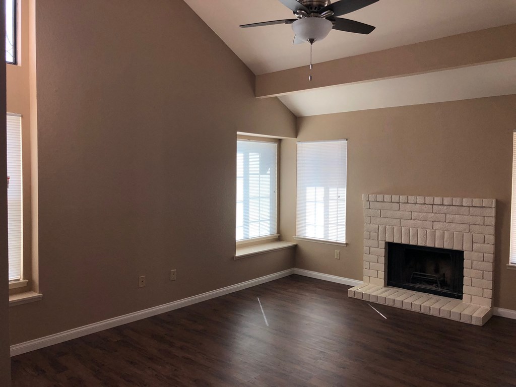 an empty living room with a fireplace and a ceiling fan