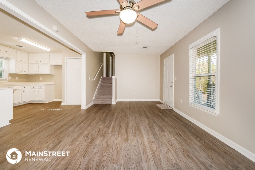 the living room and entryway of an empty house with a ceiling fan
