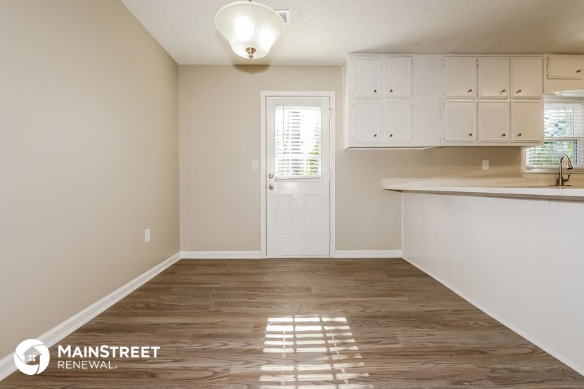 an empty kitchen with white cabinets and a white door