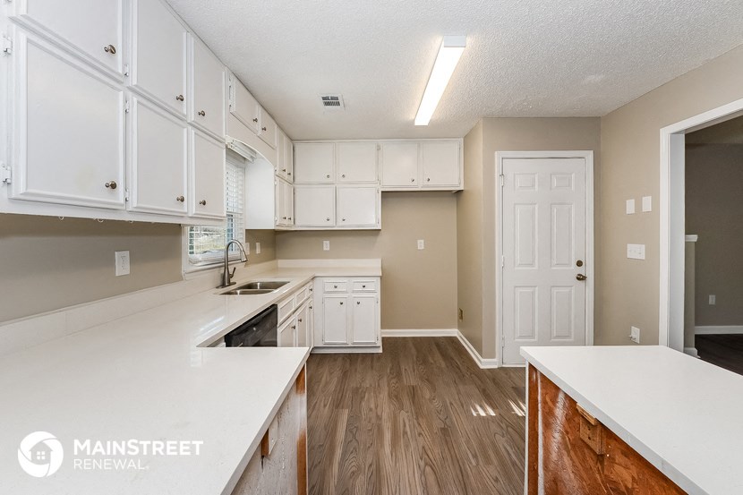 a large kitchen with white cabinets and white counter tops and a wooden floor