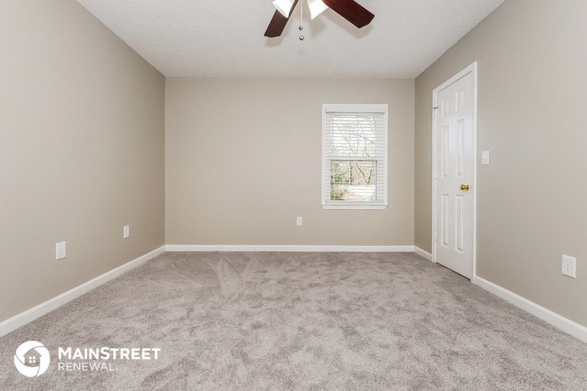 the spacious living room with carpeting and a ceiling fan