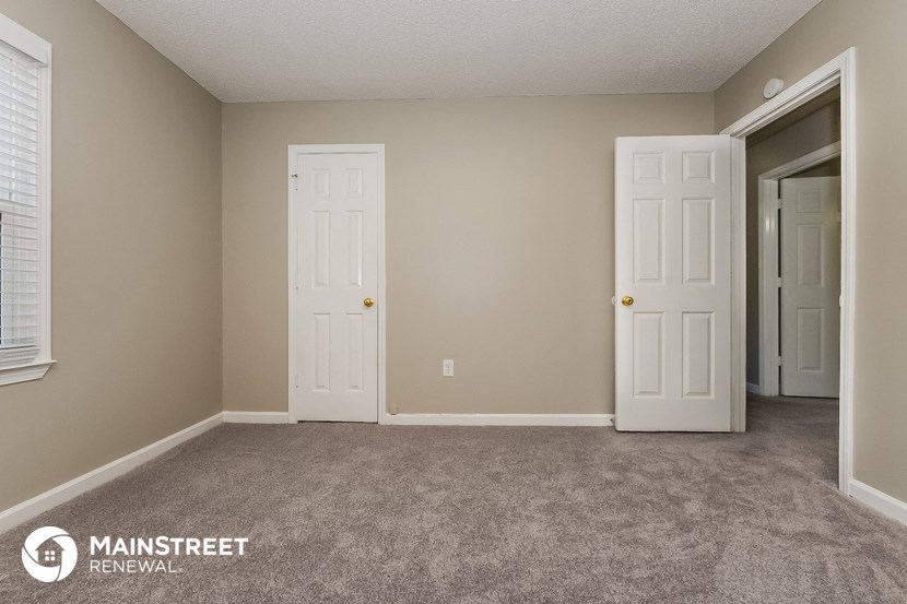 a bedroom with two doors and a carpeted floor    and a closet