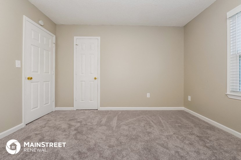a bedroom with two doors and a carpeted floor