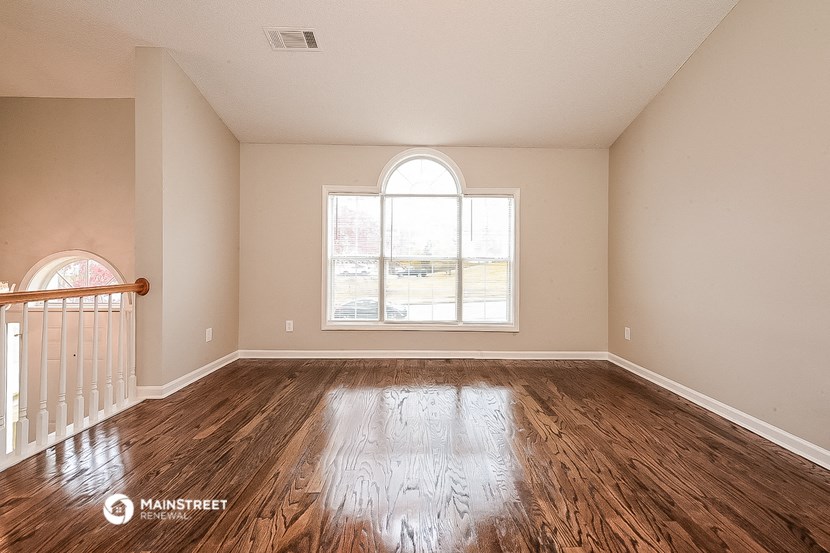an empty living room with wood floors and a large window